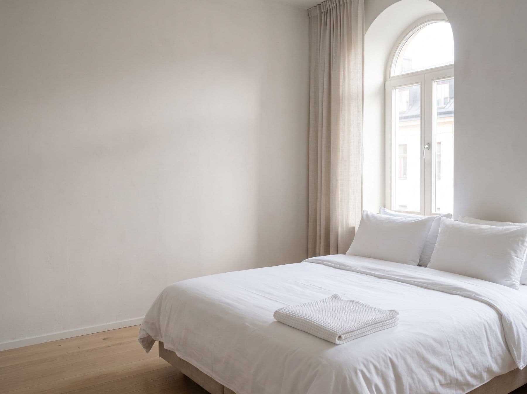 Helles Hotelzimmer mit frisch bezogenem Bett in weißer Bettwäsche